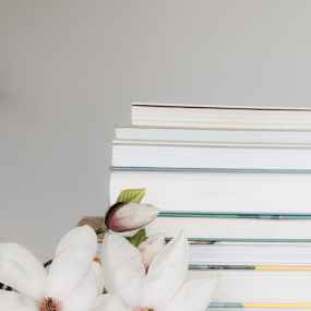 stack of books near blooming magnolia flowers